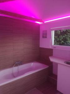 a bathroom with a tub and a pink lighting at Csudahely - WonderPlace in Dunabogdány