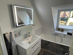 a bathroom with a sink and a tub and a mirror at FeWo Ostsee Ahoi in Timmendorfer Strand +105 photos