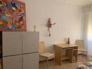 een kamer met een koelkast, een tafel en een schilderij bij CASA VACANZE MARE TORTOLI' ARBATAX in Tortolì