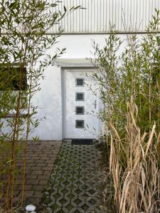 un garaje blanco con una puerta y algunas plantas en Ferienwohnung Nordlicht en Rostock
