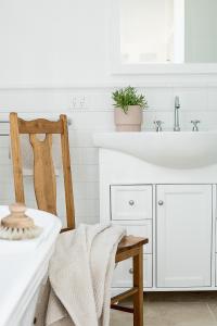 a white bathroom with a sink and a wooden chair at Old Market Inn in Port Fairy