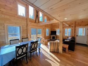 Cabaña de madera con comedor y sala de estar en 18HA Log home close to CannonFranconia Notch, en Sugar Hill