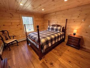 1 dormitorio con 1 cama y 1 silla en una cabaña de madera en 18HA Log home close to CannonFranconia Notch, en Sugar Hill