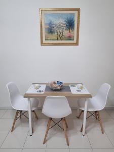 einen Tisch mit weißen Stühlen und ein Bild an der Wand in der Unterkunft B&b Binario38 in Benevento