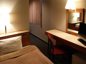 una camera d'albergo con letto e scrivania con computer di HOTEL LiVEMAX BUDGET Hiratsuka Ekimae a Hiratsuka
