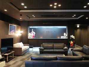una sala de estar con sofás y una pantalla grande en HOTEL LiVEMAX BUDGET Hiratsuka Ekimae, en Hiratsuka