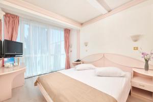 a white bedroom with a bed and a large window at Hotel Zorna Plava Laguna in Poreč