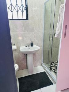 y baño con lavabo y ducha. en Sekos Guest House & Shisanyama en St Lucia