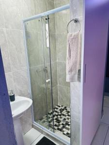 una ducha con una puerta de cristal junto a un lavabo en Sekos Guest House & Shisanyama en St Lucia