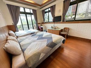 a bedroom with a bed and a desk and windows at Greeny Homestay in Ren'ai