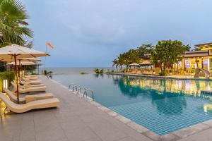 a swimming pool with chairs and umbrellas next to the ocean at Sand Dunes Chaolao Beach Resort in Chao Lao Beach
