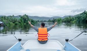 a man is sitting in a boat on the water at Peam Snea Resort in Kampot