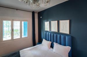a bedroom with a blue wall and a bed with pillows at La Villa Des Oliviers in Sidi Bou Saïd