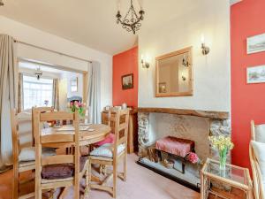 a dining room with a table and a fireplace at Harvey Cottage in Colyton