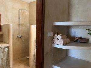 a bathroom with shelves with towels and a shower at The Garden in Paje