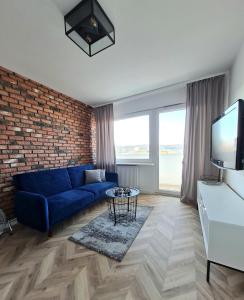 sala de estar con sofá azul y pared de ladrillo en Sun and holidays apartament Władysława IV, en Gdynia