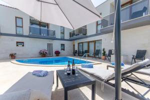a house with a swimming pool and an umbrella at Villa LA in Drvenik Veli
