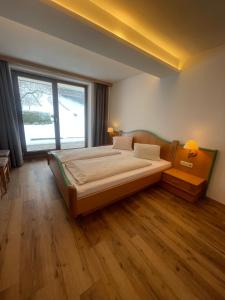a bedroom with a large bed and a large window at Hotel Gasthof Stoanerhof in Mayrhofen