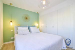 a bedroom with a large white bed and green walls at Apartamento Ohana by MTPhomes in Armação de Pêra
