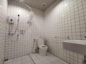 a white tiled bathroom with a toilet and a sink at DONPIN8-Timeless House Chiang Mai in Chiang Mai