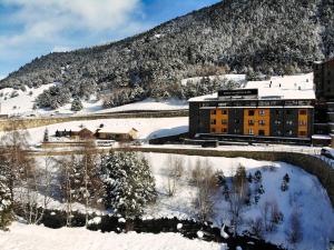 un hôtel dans la neige avec une montagne en arrière-plan dans l'établissement Wuau! Hotel Galanthus & Spa, à Soldeu