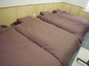 two beds sitting next to each other in a bedroom at すまいるハウス in Teine