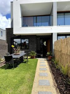 a house with a table and chairs in the yard at New & adorable unit close to the beach in Aspendale