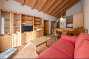 Residence Lagorai - Fiemme Holidays في بريدازو: غرفة معيشة مع أريكة حمراء وطاولة
