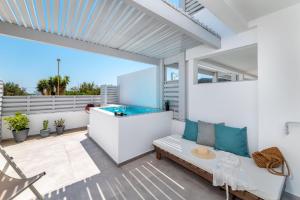 un patio al aire libre con bañera de hidromasaje y sofá en Kellys Luxury Apartments, en Faliraki