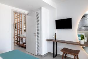 uma sala de estar com uma secretária e uma televisão na parede em Kellys Luxury Apartments em Faliraki