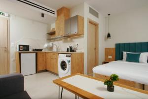 a bedroom with a bed and a kitchen with a washing machine at Oliva Suites in Keramoti