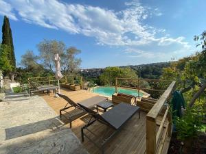 eine Holzterrasse mit einem Pool und einer Terrasse mit Stühlen in der Unterkunft 06Q - Biot - belle villa provençale avec piscine in Biot