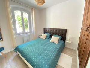 Schlafzimmer mit einem Bett mit blauer Bettwäsche und einem Fenster in der Unterkunft 06Q - Biot - belle villa provençale avec piscine in Biot