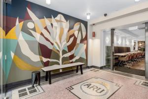 a mural in a room with a bench and a table at Alto Hotel On Bourke in Melbourne