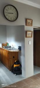 eine Küche mit einem Waschbecken und einer Uhr an der Wand in der Unterkunft Immaculate 2-Bed Garden Cottage in Beaufort West in Beaufort West