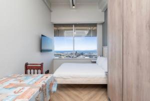 a bedroom with a bed and a large window at Cosy Studio with Spectacular Views in Cape Town