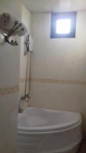 a bathroom with a shower and a toilet with a window at Tic Guest House in Liên Trì (3)