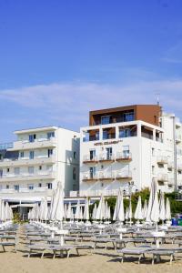 a group of chairs and umbrellas in front of a building at Hotel Columbia & Ninfea in Lido di Jesolo