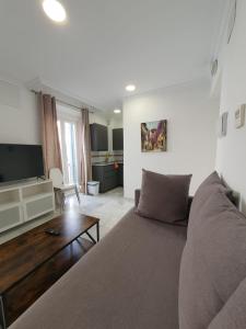ein Wohnzimmer mit einem Sofa und einem Flachbild-TV in der Unterkunft Apartamentos Los Angeles in Sevilla