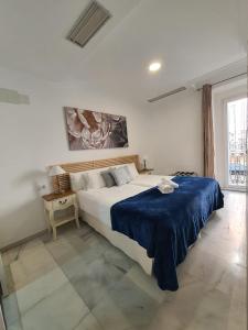 a bedroom with a large bed with a blue blanket at Apartamentos Los Angeles in Seville
