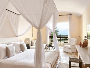 een slaapkamer met een wit bed en een baldakijn bij Grecotel-LUXME Daphnila Bay Dassia in Dassia
