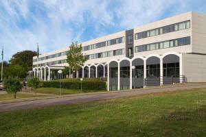 a large white building with a road in front of it at Comwell Kolding in Kolding