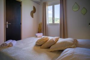 a bedroom with a bed with two pillows and a window at Hôtel - Restaurant U Santu Petru in Saint-Florent