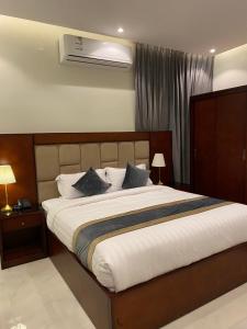 1 dormitorio con 1 cama blanca grande con almohadas en فندق الأفنيوز بالرس en Al Rass