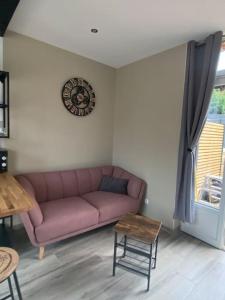 uma sala de estar com um sofá rosa e uma mesa em O'Ptit Roupillon By Mel & Jérôme 