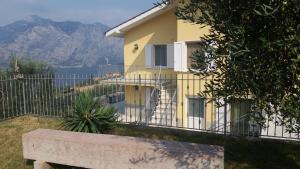 uma casa amarela com uma cerca e montanhas ao fundo em Appartamenti Ceccherini em Malcesine