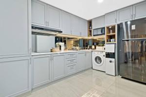 a kitchen with white cabinets and a washer and dryer at Mahadara by Kozystay Bandung in Bandung