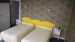 - une chambre avec 2 lits et une tête de lit jaune dans l'établissement Hotel Saint Jean, à Chalon-sur-Saône