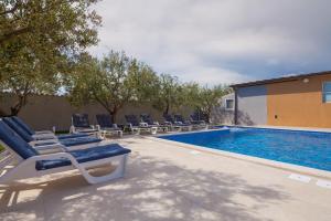 a swimming pool with lounge chairs next to a building at Villa Mirjana in Banjole