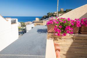 a person standing on a ledge with flowers on a balcony at Casa Clelia Piazza in Ustica